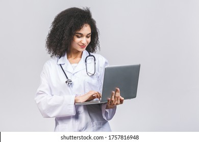 Beautiful Young African American Black Woman Doctor Or Nurse Isolated Over White Or Grey Background. Using Laptop Computer.