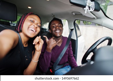 Beautiful young african american couple sitting on the front passenger seats while handsome man driving a car. Making selfie together. - Powered by Shutterstock