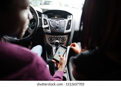 Beautiful Young African American Couple Sitting On The Front Passenger Seats While Handsome Man Driving A Car. Looking At Map On Phone.