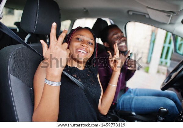 Beautiful young african american couple sitting on\
the front passenger seats while handsome man driving a car.\
Listening music and\
dance.