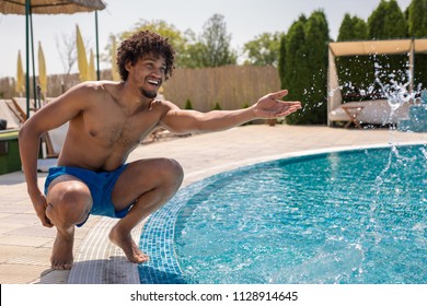 Beautiful Young African American Man Splashing Water At A Pool Outisde