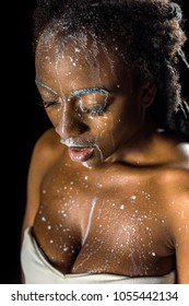 Beautiful Young African American Woman With Spilled Milk On Face Isolated On Black