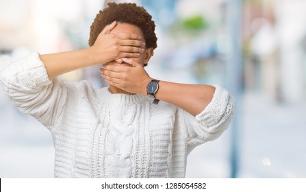 Beautiful young african american woman wearing sweater over isolated background Covering eyes and mouth with hands, surprised and shocked. Hiding emotion