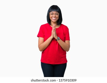 Beautiful Young African American Woman Wearing Glasses Over Isolated Background Praying With Hands Together Asking For Forgiveness Smiling Confident.