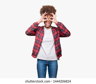 Beautiful Young African American Woman Wearing Glasses Over Isolated Background Doing Ok Gesture Like Binoculars Sticking Tongue Out, Eyes Looking Through Fingers. Crazy Expression.