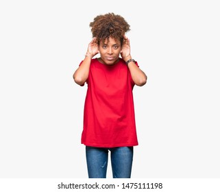 Beautiful young african american woman over isolated background Trying to hear both hands on ear gesture, curious for gossip. Hearing problem, deaf