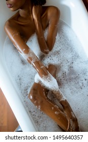 Beautiful young african american woman bathing in a tub full of foam