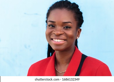 a beautiful young african american woman with pigtails hairstyle in a red business suit on a blue background