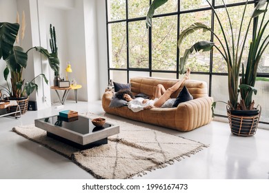 Beautiful And Young African American Woman Sleeping On A Couch In A Big Bright Living Room. Home Concept. Copy Space