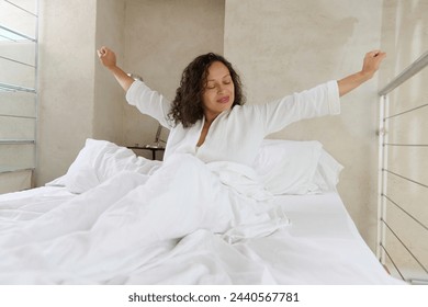 Beautiful young African American young woman stretching in the bed while waking up in the morning. Resting, smile and female stretch in her bedroom, content and peaceful, cheerful and comfortable - Powered by Shutterstock