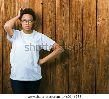 Beautiful young african american woman wearing glasses over isolated background confuse and wonder about question. Uncertain with doubt, thinking with hand on head. Pensive concept.