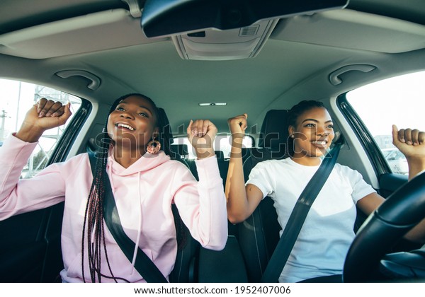 Beautiful young african\
american women sitting on the front passenger seats while handsome\
man driving a car.