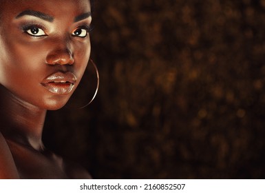 Beautiful young African woman with bright make up posing against a gold background.