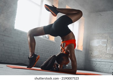 Beautiful young African woman doing handstand splits in gym - Powered by Shutterstock