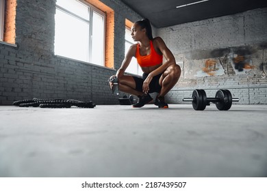 Beautiful Young African Woman Holding Bottle With Water While Taking A Break In Gym