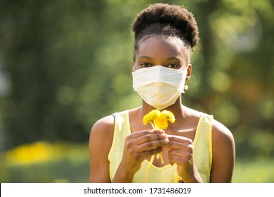 Beautiful Young African Woman In Medical Mask With Flowers In Her Hands