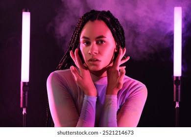 Beautiful young African-American woman with braids and neon lamps on dark background - Powered by Shutterstock