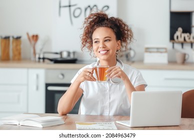 Beautiful young African-American woman drinking hot tea at home