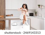 Beautiful young African-American woman eating ice cream in kitchen