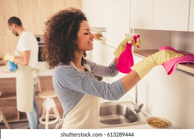 Beautiful young Afro American couple is cleaning kitchen. Girl is smiling - Powered by Shutterstock