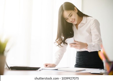 Beautiful Young Asia Woman Working With Smart Phone In Office