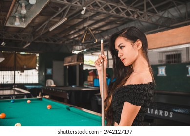 A Beautiful And Young Asian Billiard Player At An Open Air And Old Pool Hall. Third World And Exotic Ambiance.