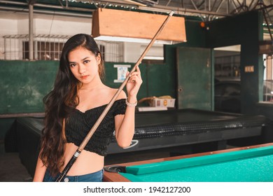 A Beautiful And Young Asian Billiard Player At An Open Air And Old Pool Hall. Third World And Exotic Ambiance.