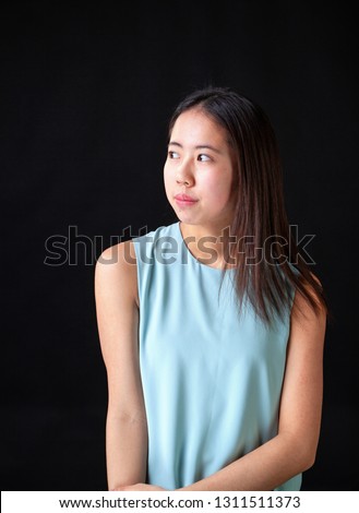 Beautiful young Asian female teen model posing in studio on black background.