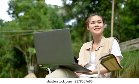 Beautiful Young Asian Female Using Portable Laptop Computer While Looking At The Beautiful View Of Nature Forest. Camping And Businesswoman Concept