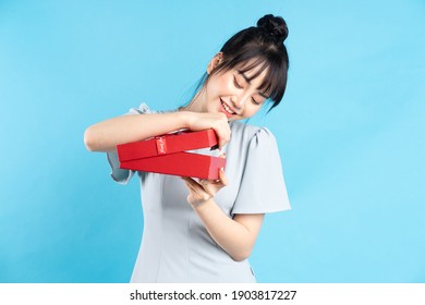 Beautiful Young Asian Girl Holding Red Gift Box On Blue Background
