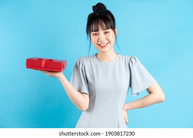 Beautiful Young Asian Girl Holding Red Gift Box On Blue Background
