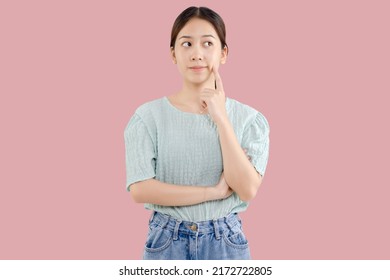 Beautiful young Asian girl thinking and looking upwards. The concept of content thinks about future isolated on pink background.