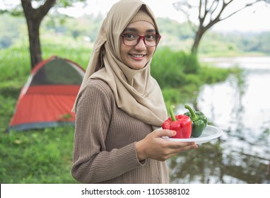 Beautiful Young Asian Muslim Woman With Paprica Preparing For Dinner While Camping In The Wood