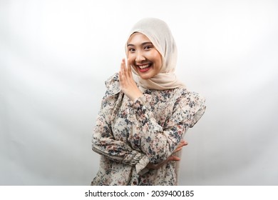 Beautiful young asian muslim woman smiling confidently and excitedly close to camera, whispering, telling secrets, speaking quietly, silent, isolated on white background