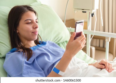 Beautiful Young Asian Patient Women Lying In Hospital Bed And Smiling With Smart Mobile Phone While Recovering In Hospital. Recovering Patient Women Happy Working On Business Mobile Phone In Hospital.