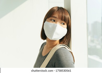 Beautiful Young Asian Thai Black Short Hair Woman Wearing White Surgical Mask Looking Outside The Window.