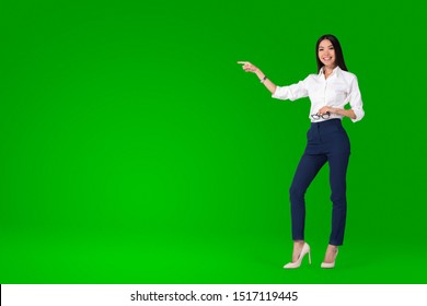 A beautiful young asian woman, anchor or tv presenter is getting filmed inside a green screen chroma key studio to create a video with removable background that can be replaced