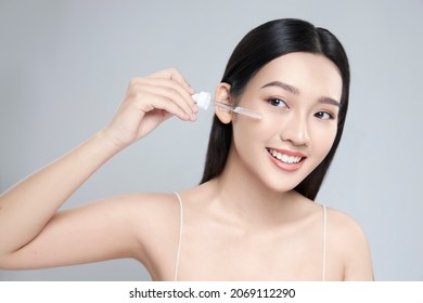 Beautiful young asian woman apply facial serum isolated on light grey background. Skin care and rejuvenation. - Shutterstock ID 2069112290
