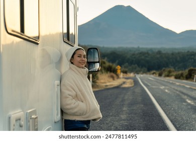 Beautiful young asian woman with beanie leaning on motorhome and volcano mountain by the roadside in the morning at New Zealand - Powered by Shutterstock