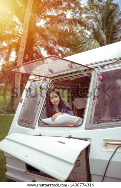 Beautiful young asian woman in a camper van on a
summer day
