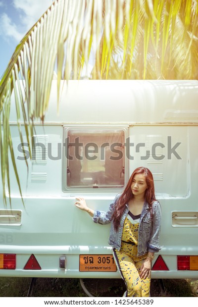 Beautiful young asian woman in a camper van on a\
summer day