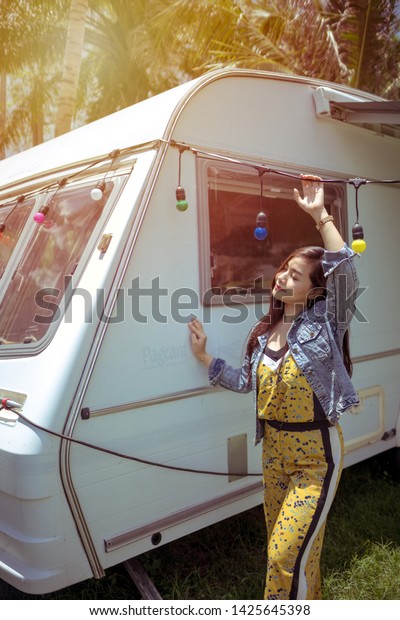 Beautiful young asian woman in a camper van on a\
summer day