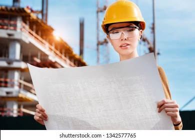 A Beautiful Young Asian Woman Civil Engineer Or Architect Is Reviewing Engineering Plans In Front Of A Construction Site