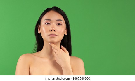 Beautiful young asian woman with clear fresh skin isolate on green background. Spa, facials, facials, beauty and cosmetics concept. Touching the neck with the left hand. Banner frame