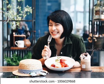 Beautiful young Asian woman eating homemade pancakes in coffee shop,food blogger.