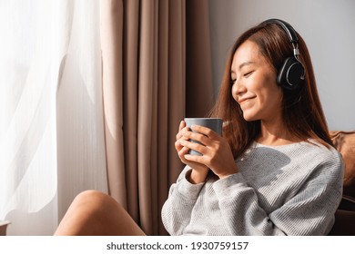 A Beautiful Young Asian Woman Enjoy Drinking Coffee And Listening To Music With Headphone At Home