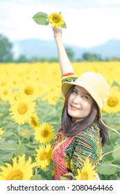 Beautiful young asian woman in a field of sunflowers in a colorful casual dress