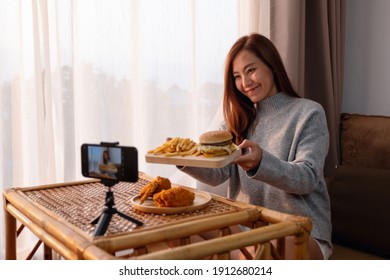 A Beautiful Young Asian Woman Food Blogger Or Vlogger Showing And Recording A Live Video Of Fried Chicken And Hamburger