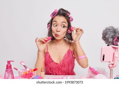 Beautiful Young Asian Woman Gives Master Class About Make Up Applies Mascara Shoots Promo Video Content With Smartphone Films How To Apply Professional Visage Makes Hairstyle Poses At Table.