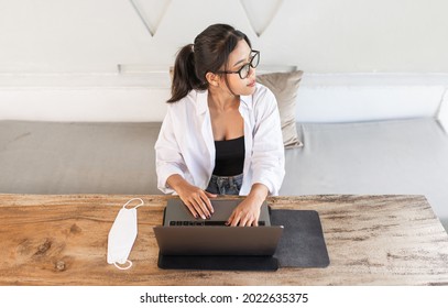 Beautiful Young Asian Woman With Glasses Using And Working On A Laptop Computer In A Cafe.
